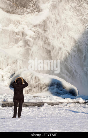 Junge Frau mit dem Fotografieren am Skogafoss Wasserfall im Winter-Wunderland mit gefrorenem Wasser und Eiszapfen Island im Januar Stockfoto