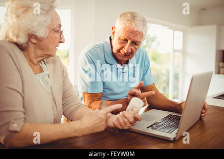 Älteres Paar mit Laptop und holding Pillen Stockfoto