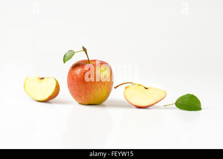 ganze und geschnittene gewaschene Äpfel mit Blättern auf weißem Hintergrund Stockfoto