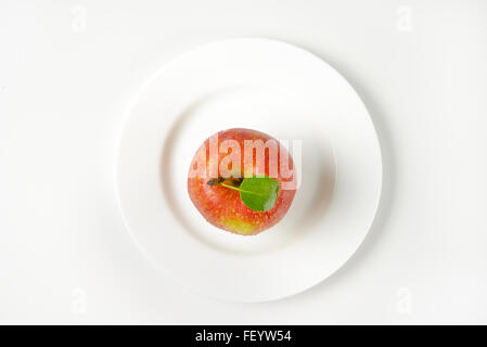 roten Apfel mit Blatt auf weißen Teller gewaschen Stockfoto