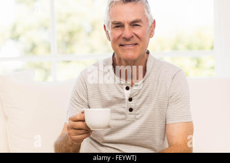 Lächelnder senior Mann hält Becher Stockfoto