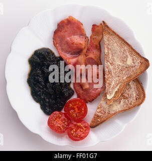 Teller mit gebratenem Speck, Kirschtomaten, Scheiben Toast und Laverbread hergestellt aus Algen, ein traditionelles Frühstück aus Wales, Ansicht von oben Stockfoto