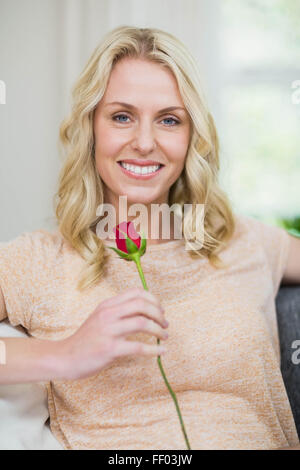 Hübsche Frau eine Rose riecht Stockfoto