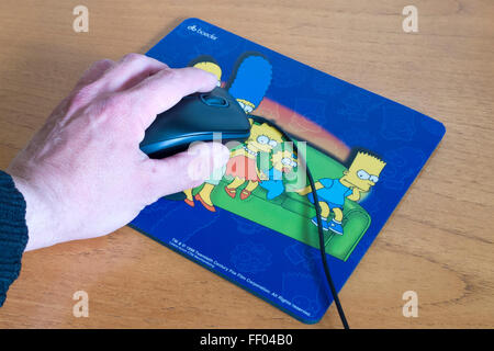 Kaukasischen Mann Hand mit einer Computer-Maus mit Simpson Mauspad, UK-Modell veröffentlicht Stockfoto