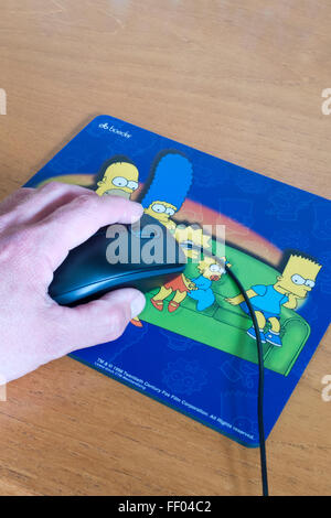 Kaukasischen Mann Hand mit einer Computer-Maus mit Simpson Mauspad, UK-Modell veröffentlicht Stockfoto