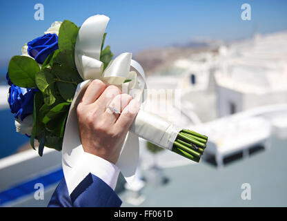 Mannes Hand hält Brautstrauß auf einem Hintergrund von weißen Gebäuden Stockfoto