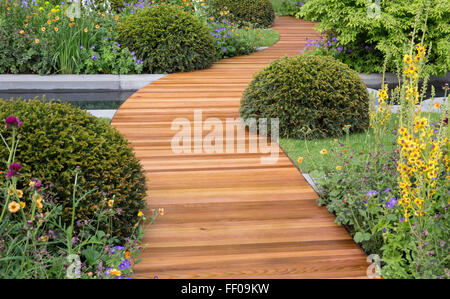 Ein moderner Gartenweg in einem urbanen Landgarten mit Weg Eibenkugeln Topiary und Blumenrand Blumen Grenzen Großbritannien Stockfoto