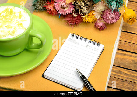 Leere Notebook mit Tasse Cappuccino auf Tisch Stockfoto