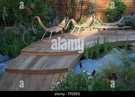 Kleiner, moderner Garten mit Holzterrasse im Freien Gartenmöbel Sitzbereich über dem Wasser, Teich bei der Chelsea Flower Show london UK Stockfoto