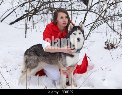 Mädchen im roten Umhang mit Siberian Husky Stockfoto