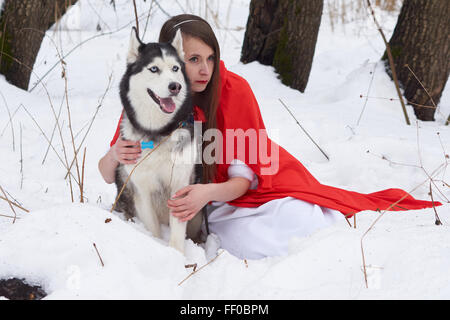 Mädchen im roten Umhang mit Siberian Husky Stockfoto