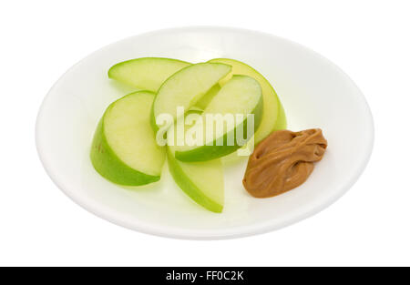 Eine Gruppe von grünem Apfelscheiben auf einen Teller mit einer kleinen Portion Erdnussbutter zum Dippen isoliert auf einem weißen Hintergrund. Stockfoto