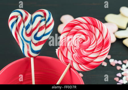 Lollipop und eine Runde Lutscher in einer roten Vase in Herzform Stockfoto
