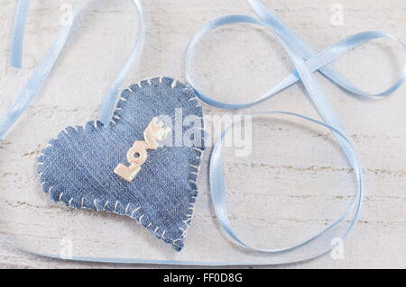 Denim-Herz mit dem Wort Liebe drauf gelegt auf eine hölzerne Tafel Stockfoto