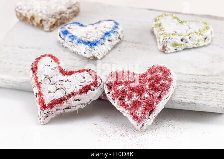 Süßes Gebäck auf einem weißen Holzbrett in Herzform Stockfoto