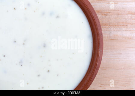 Enge Draufsicht eine kleine Schüssel mit Ranch Dressing auf einer hölzernen Tischplatte mit natürlichem Licht beleuchtet. Stockfoto