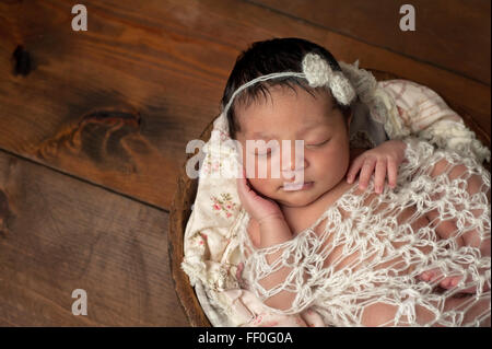 Neugeborenes Babymädchen schlafen in einer fötalen Position Stockfoto