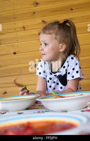 kleines Mädchen isst Suppe in der Laube Stockfoto