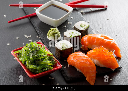 Sushi und grünem Seetang Salat auf einem Schiefer Tisch. Stockfoto