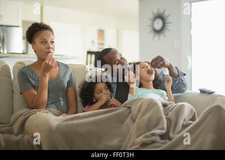 Familie in Decke Naschen auf sofa Stockfoto