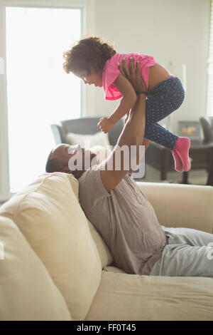 Vater und Tochter spielen auf sofa Stockfoto