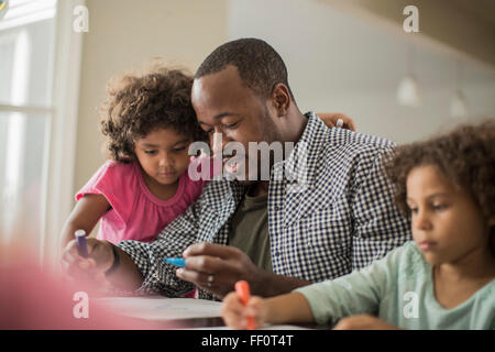 Vater und Töchter zeichnen am Tisch Stockfoto