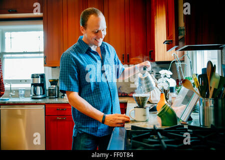 Kaukasischen Mann gießen Kaffee in der Küche Stockfoto