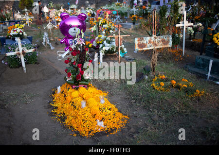 Spielzeug und gelben Ringelblumen, bekannt als Cempasuchil, dekorieren ein Grab auf dem Friedhof in San Gregorio Atlapulco, Xochimilco Stockfoto