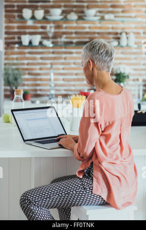 Ältere Frau kaukasischen mit Laptop in der Küche Stockfoto