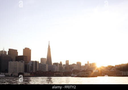 Blick auf die Skyline der Innenstadt San Francisco, darunter das Transamerica Building mit die untergehende Sonne hinter dem Horizont. Stockfoto