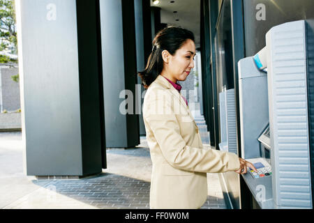 Asiatische Geschäftsfrau mit ATM im freien Stockfoto