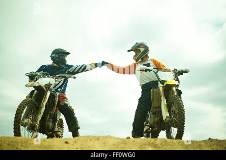 Kaukasische Männer stoßen Fäuste auf Dirtbikes Stockfoto