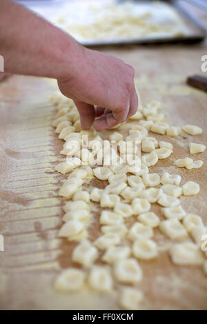 Nahaufnahme einer Hand bereitet hausgemachte Gnocchi auf einem hölzernen Theke bedeckt mit einer Schicht aus Grieß Mehl. Stockfoto