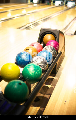 Eine bunte Auswahl an Bowling-Kugeln aufgereiht am ball Maschine in einer Bowlingbahn. Stockfoto