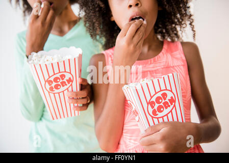 Gemischte Rassen Schwestern Essen popcorn Stockfoto