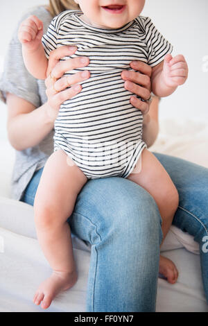 Kaukasische Mutter hält Tochter auf Bett Stockfoto