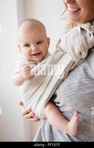 Kaukasische Mutter hält Tochter im Tragetuch Stockfoto