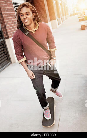 Gemischte Rassen Mann reitet Skateboard auf Bürgersteig Stockfoto