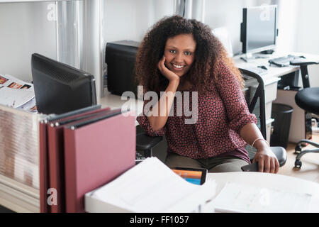 Schwarzen Geschäftsfrau lächelnd am Schreibtisch Stockfoto