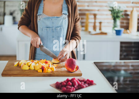 Kaukasische Frau Hacken Obst in Küche Stockfoto