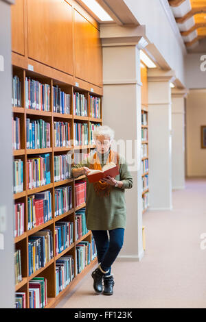 Ältere Mischlinge Frau Lesebuch in Bibliothek Stockfoto