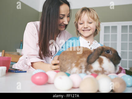 Glückliche junge Frau und ihr Sohn spielen mit Osterhase Stockfoto