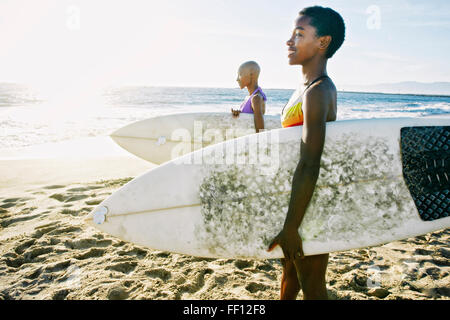 Schwarze Frauen, die die Surfbretter am Strand Stockfoto