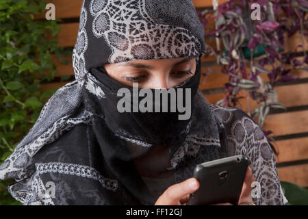 Hispanic Frau im Kopftuch mit Handy Stockfoto