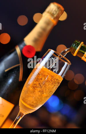 Champagner in Longdrinkglas gießen Stockfoto