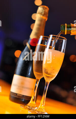 Champagner in Longdrinkglas gießen Stockfoto