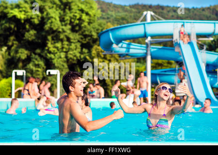 Junges Paar im Schwimmbad an sonnigen Tag. Wasserrutsche. Stockfoto