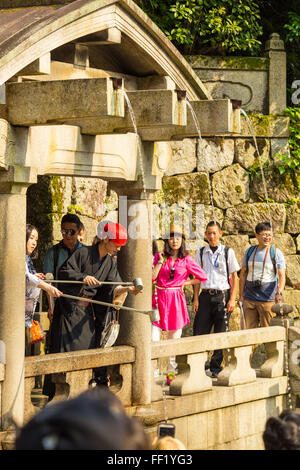 Touristen an der Basis des Kiyomizu-Dera Tempel Schlange zu trinken Wasser mit Tassen mit langen Stab Griffe am Otowa-keine-ta Stockfoto