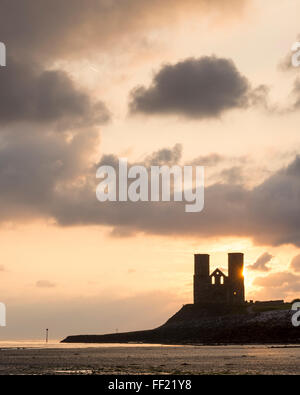 Die Sonne hinter die Zwillingstürme des St.-Marien Kirche in Reculver auf der Küste von North Kent. Stockfoto