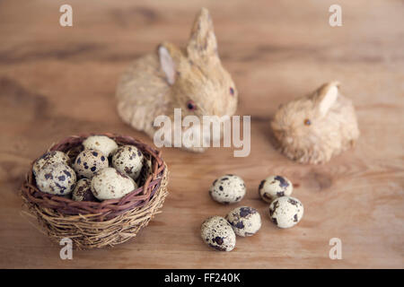 Stroh Osterhase mit Korb von der Wachtel-Eiern auf Holztisch Stockfoto